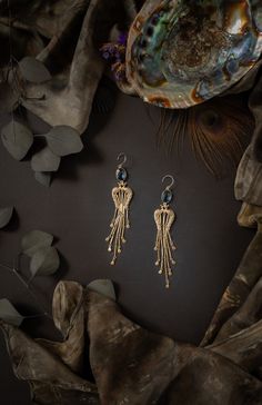 "A temple to the goddess of love is within us all. Dedicated to beauty, the temple walls are in-layed with gemstones and inscribed with symbols of grace and splendor. This tasselpiece reminds you that you and she are never distant from one another. These lightweight statement earrings feature a kissing peacock motif and handmade tassels with scallop details. They hang from vibrant gemstones.  Earrings hang 4.5\" to gently caress the shoulders.  -Tooled brass charms and chain with antique gold ov Celebration Jewelry With Tassels, Long Drop Tassel Chandelier Earrings As A Gift, Long Drop Chandelier Earrings With Tassels For Gifts, Celebration Tassel Jewelry, Long Drop Chandelier Earrings With Tassels, Gold Chandelier Earrings With Peacock Design As Gift, Artisan Gold Jewelry With Tassels, Bohemian Jewelry With Peacock Design For Rituals, Peacock Design Dangle Chandelier Earrings Gift