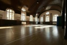 an empty room with wooden floors and large windows in the center is lit by sunlight coming through three arched windows