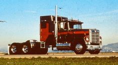 a red and black semi truck driving down the road