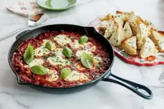 an iron skillet filled with pasta and spinach garnished with parmesan cheese