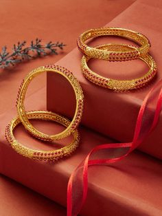 These Golden Ruby Bangles exude opulence and sophistication with their vibrant ruby accents set against a warm golden hue. The striking combination of rich red rubies and elegant gold creates a dazzling accessory that enhances any ensemble. Elegant Bangle For Diwali Celebration, Red 22k Gold Jewelry With Intricate Design, Gold Ruby Round Jewelry, Gold Ruby Jewelry With Round Shape, Red Hand Set Bangle For Festivals, Ruby Temple Jewelry Bracelets For Festivals, Hand Set Red Bangle For Festivals, Yellow Gold Ruby Jewelry, Festive Ruby Jeweled Bracelets