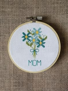 a cross - stitch flower bouquet with the word mom on it