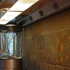 a blender sitting on top of a counter next to a wall mounted oven hood