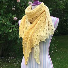 a yellow knitted scarf on top of a mannequin in front of trees