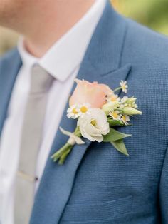 a man wearing a blue suit and flower boutonniere with white flowers on the lapel