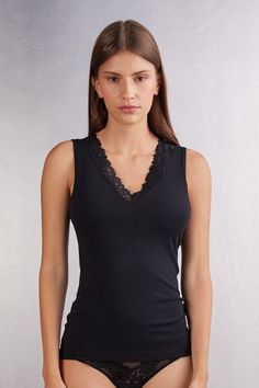 Soft modal tank top with neckline trimmed with an elegant floral motif lace ruffle. V-neck Tank Top With Lace Trim For Daywear, Elegant V-neck Tank Top With Lace Trim, Elegant Sleeveless Lace Top With Built-in Bra, Chic Sleeveless Tops With Delicate Lace, Elegant Stretch Lace Top Camisole, Elegant Modal Camisole, Black Feminine Sleeveless Camisole, Feminine Delicate Lace Sleeveless Tank Top, Elegant Stretch Lace Cami Top