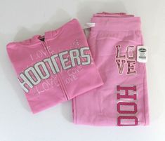 1 - LOVE HOOTERS AUTHENTIC SEXY PINK SWEATPANTS & SWEATSHIRT OUTFIT JACKET: SIZE: SMALL 80% COTTON / 20% POLYESTER MEASURES APPROX. ARM PIT TO ARM PIT: 17.5" FLAT / 35" ROUND MEASURES APPROX FROM SHOULDER TO BOTTOM OF SHIRT: 22" ZIPPER IS FROM TOP TO BOTTOM (COMPLETELY COMES APART) FRONT OF JACKET/TOP HAS SEQUINS AROUND THE LETTERS OF HOOTERS  WITH MISC WHITE GEM STONES  BRAND NEW WITH TAGS! ANGLE SWEATPANTS: SIZE: - MEDIUM / M 80% COTTON / 20% POLYESTER HAS SEQUINS AROUND THE LETTERS OF LOVE ON Pink Bling Clothes, Affordable Trendy Hello Kitty Top, Pink Y2k Hoodie For Fall, Pink Letter Print Sweats For Streetwear, Pink Y2k Hoodie, Sweatpants And Sweatshirt Outfit, Comfy Mcbling Outfits, Western Sweatshirts Pink, Fitness Fashion Active Wear