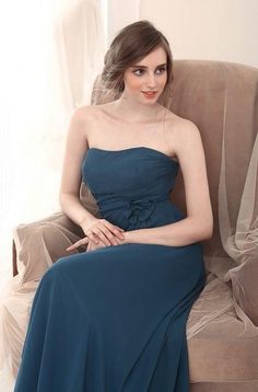 a woman sitting in a chair wearing a blue dress and posing for the camera with her hands on her hips