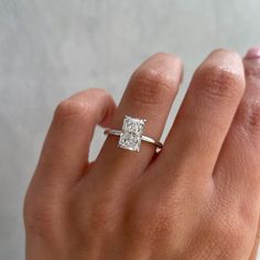 a woman's hand with a diamond ring on top of her finger, showing the center stone