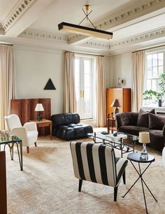 a living room filled with lots of furniture next to a large window covered in curtains