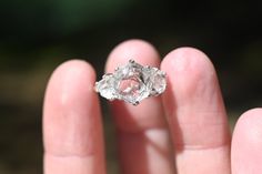 a close up of a person's hand holding a ring with a diamond in it