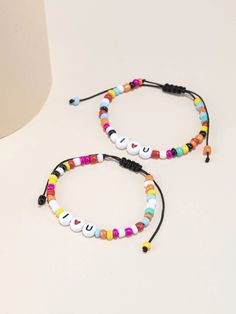 two bracelets with colorful beads are sitting on a white table next to a lamp