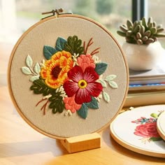 a close up of a embroidery on a table near a potted plant and plate