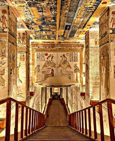 an egyptian style hallway with paintings on the ceiling and stairs leading to another room that is decorated in gold, blue, and white