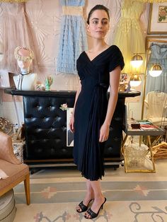 "Vintage 1950's black cotton dress with silk chiffon pleated cross-over detail at bodice with satin bow and dramatic sash - Major Marvelous Mrs. Maisel vibes! Fit: Small Bust: up to 36\" Waist: up to 30\" Hips: 39\" Length: 42\" Condition: Excellent Vintage Condition. All sales are final. Thank you for shopping small and sustainable." Silk Dresses With Accordion Pleats For Evening, Silk Evening Dress With Pleated Waist, Silk Pleated Waist Dress For Evening, Dressy Fitted Pleated Evening Dress, Silk Cocktail Dress With Accordion Pleats, Cocktail Silk Dress With Accordion Pleats, Fitted Silk Pleated Dress For Gala, Fitted Silk Pleated Dress For Evening, Silk Pleated Evening Dress