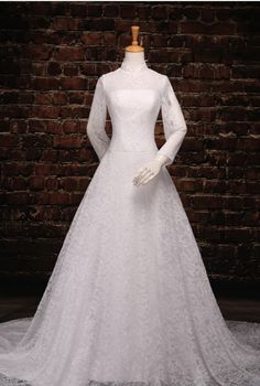 a white wedding dress on display in front of a brick wall