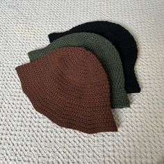 three hats laying on top of each other on a white bed sheet with a crochet pattern