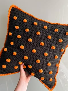 a crocheted pillow with pumpkins on it is being held by a hand