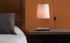 a lamp that is on top of a night stand next to a bed with pillows