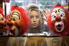 a woman is surrounded by three clown masks