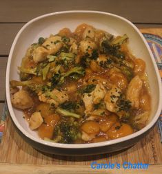 a white bowl filled with chicken and broccoli on top of a wooden cutting board