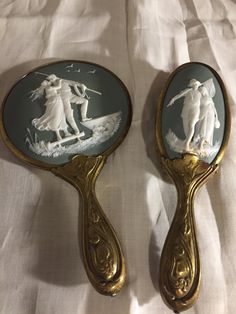 two mirrors that are sitting on top of a white bed sheet, one has an image of a man and woman