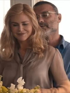 a man and woman sitting at a table with flowers in front of them