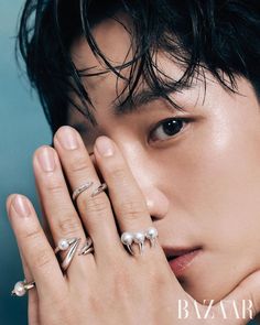 a young man is holding his hand up to his face with two rings on it