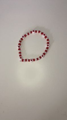 a red and white beaded bracelet sitting on top of a table