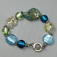 Vintage Art Glass Bracelet Blue Green Clear Beads Wavy Twist Speckled Foil 6.5" Unique Blue Beaded Bracelets With Polished Beads, Blue Glass Beaded Bracelets For Jewelry Making, Vintage Blue Beaded Bracelets With Round Beads, Unique Blue Bracelets With Large Beads, Blue Glass Bracelets With Spacer Beads, Green Glass Bracelets With Colorful Beads, Vintage Handmade Glass Bracelets, Blue Glass Bracelet Jewelry, Blue Glass Bracelet With Spacer Beads