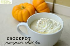 a white cup filled with whipped cream next to two pumpkins