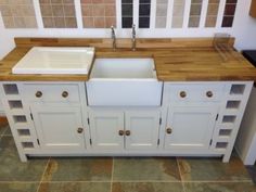 a white kitchen sink sitting under a window next to a counter top with drawers and cupboards