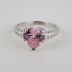 a pink heart shaped ring with diamonds around it