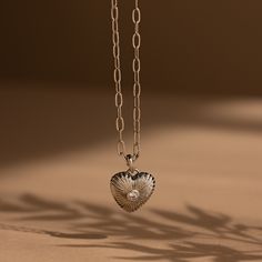 Get ready to fall in love with our Diamond Ribbed Heart Pendant! With its vintage-inspired design and diamond centerpiece, this pendant embodies charm and allure, making it the perfect accessory to showcase your flirtatious style with a hint of elegance. SKU: RR-NR214 Product Details Finish/Material: 18K Gold Over Brass ∙ White Gold Over Brass Featuring a ~15x15.5mm Heart Charm with embedded ~3mm Diamond CZ Gemstone on a Paper Clip Chain, adjustable from 16 to 18 inches Featured Styles Part of o Heart Pendant Necklace With Vintage Charm For Anniversary, Vintage Heart Pendant Necklace For Anniversary, Elegant Jewelry Charms, Anniversary Heart Pendant Necklace With Vintage Charm, Elegant Heart Pendant Necklaces With Charms, Elegant Heart Pendant Necklace With Vintage Charm, Vintage Sterling Silver Heart Charm Necklace, Elegant Heart Shaped Charms Necklace, Elegant Heart-shaped Charms Necklace