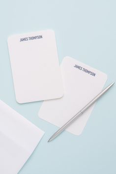 two business cards and a pen on a blue background with the name james thompson written on them