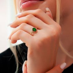 a close up of a person wearing a ring with a green gemstone on it