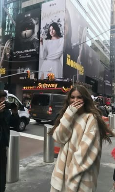 a woman is walking down the street talking on her cell phone while holding her hand to her face