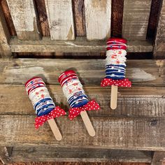 three red, white and blue toothpicks are sitting on top of a wooden bench