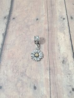 "Cute daisy pendant on European style bail. (1 sided) You will receive 1 pendant. The daisy is zinc alloy and the bail is silver plated base metal. Perfect for necklaces, charm bracelets, zipper pulls, or other crafting needs! Approximate size:  1/2\" x 2/5\" bail & 2/3\" x 1/2\" daisy pendant. Made in USA" Silver Flower Charms For Gifts, Silver Sunflower Pendant Jewelry, Silver Jewelry With Sunflower Design Flower Pendant, Silver Flower Charm Pendant, Silver Flower Charms Jewelry, Dainty Silver Metal Charms, Dainty Silver Charms For Mother's Day, Dainty Adjustable Silver Charms, Dainty Silver Sunflower Jewelry