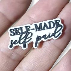 a hand holding a black and white sticker that says self - made self pride