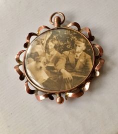 Edwardian 9 Ct rose gold 2 sided photo mourning pendant with dated photographs circa 1800's. This beautiful fine pendant jewelry is hallmarked 9 ct and is from Europe from the 1900's. It's is the condition there are no rips on the plastic that covers the respective photographs which are well preserved. The rose gold has patina on it to authenticate the age of this beautiful piece of period jewelry. This will be a great addition to an Edwardian jewelry collection. Commemorative Pendant Locket Jewelry, Antique Medallion Jewelry For Commemoration, Antique Commemoration Medallion Jewelry, Memorial Bronze Locket Jewelry, Bronze Locket For Memorial Occasions, Antique Bronze Jewelry For Commemoration, Antique Pendant Necklace For Commemoration, Victorian Bronze Keepsake Jewelry, Antique Pendant Jewelry For Commemoration