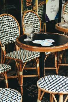 three wicker chairs sitting around a table with two empty wine glasses on top of it