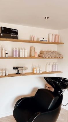 a hair salon with shelves filled with bottles and shampoos on the wall next to a black chair