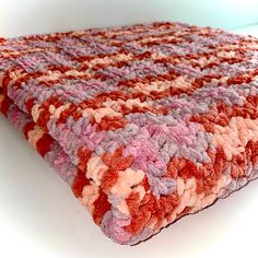 a multicolored crocheted blanket laying on top of a white table