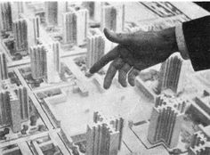 a hand reaching for something in the middle of a city with buildings and skyscrapers