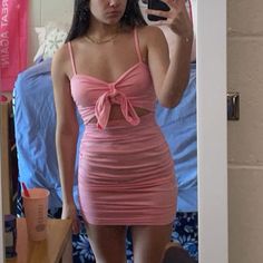 a woman taking a selfie in a mirror wearing a pink dress and holding a cell phone