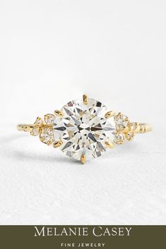 a yellow gold engagement ring with an oval cut diamond surrounded by three smaller round diamonds