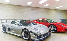 two sports cars parked in a garage next to each other