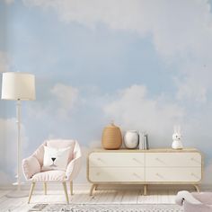 a room with a dresser, chair and wallpaper on the walls that has clouds painted on it