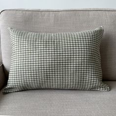 a gray and white pillow sitting on top of a couch